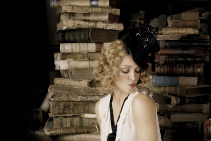 Das Mädchen trägt einen schwarzen Hut. Das Mädchen ist in der Bibliothek. Alte Bücher. Hexe