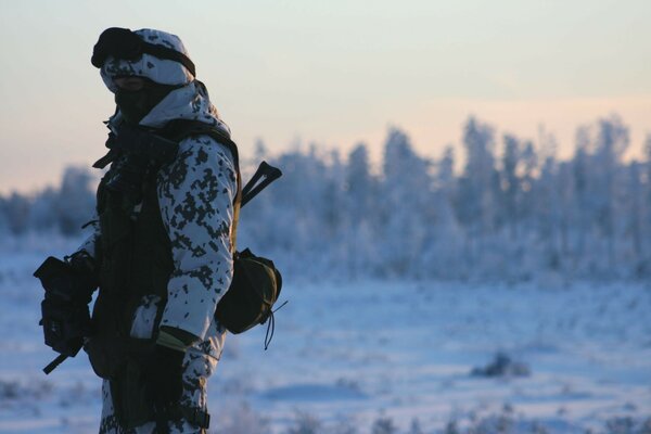 Mann in Tarnung vor dem Hintergrund einer Winterlandschaft
