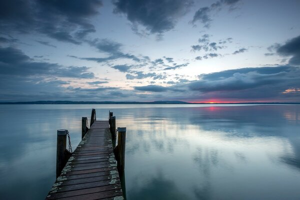 Eine schmale Brücke geht bei Sonnenuntergang in den See